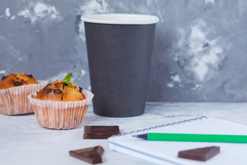 Coffee break with chocolate muffins, notebook and pencil