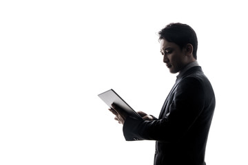 Silhouette of businessman looking tablet PC.