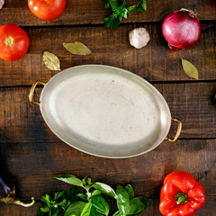 Around the vintage pan different vegetables on wooden table