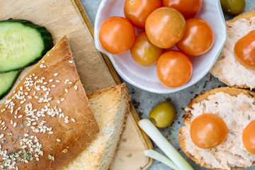 Top view of a crusty baguette slices with cherry tomatoes, cucumbers and green olives, cream cheese