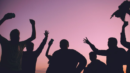 Silhouette of Group young dancing people have a party at beach on sunset
