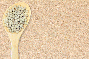 Peppercorn. White pepper in wooden spoon on cork board background for design with copy space for text or image.