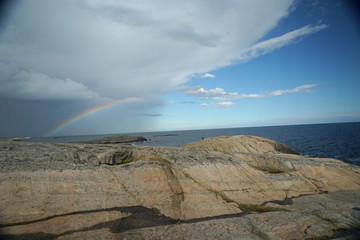 Regenwolken, blauer Himmel und Regenbogen an der Schärenküste, Südnorwegen