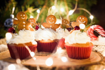 Gingerbread cupcakes, gingerbread cookies and Christmas lights. Closeup view, horizontal composition, selective focus