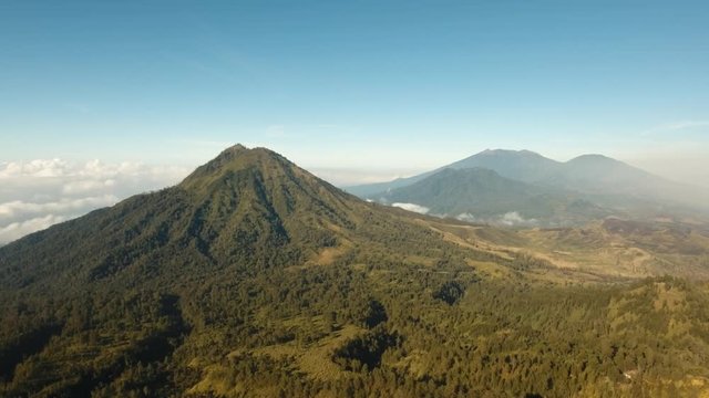 Flight over the mountains in the early morning. Aerial view of Green tropical mountain cover with cloud Banyuwangi Regency of East Java, Indonesia. 4K Aerial footage.