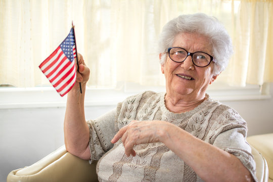 Portrait of happy senior woman holding USA flag.
