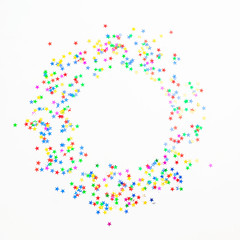Round frame of colorful confetti on white background. Flat lay, top view