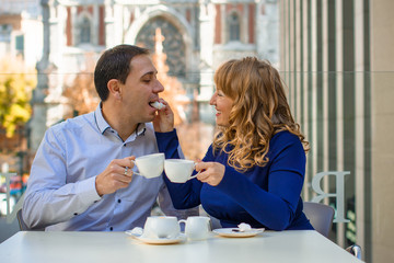 Couple of happy tourists drinking coffee on european city street in outdoors cafe, talking having fun laughing smiling happy summer holidays and dating concept in the city