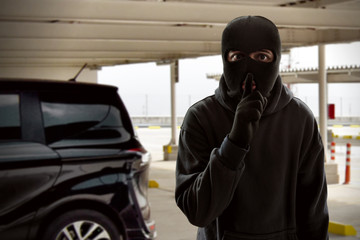 Masked thief trying to steal a car