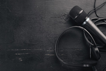 Headphones and microphone on a wooden black table. Studio. Top view. Free space for text. Copy...