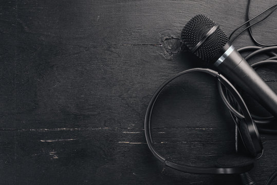 Headphones and microphone on a wooden black table. Studio. Top view. Free space for text. Copy space.