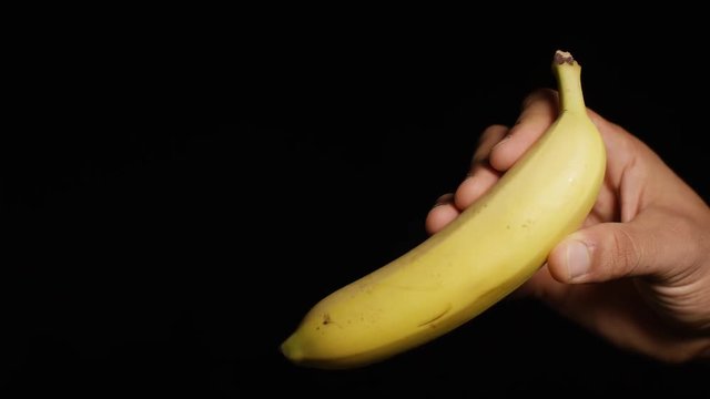Male hand holding up a banana to camera, with space for text