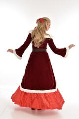  full length portrait of pretty blonde lady wearing red and white christmas inspired costume gown, standing pose on white background.