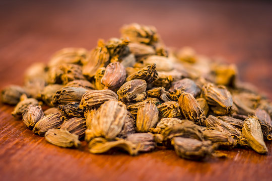 Raw black cardamom on a brownish wooden surface.