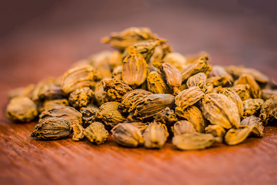 Raw black cardamom on a brownish wooden surface.