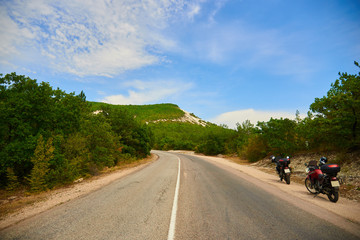 Two motorbikes on a road leading to mountain