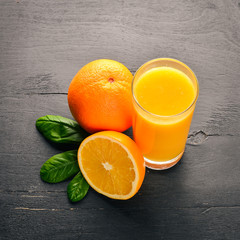Orange fresh juice and oranges on a wooden surface. Top view. Free space for text.