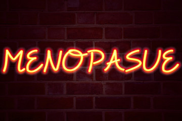 Menopause neon sign on brick wall background. Fluorescent Neon tube Sign on brickwork Business concept for Midlife Crisis Grand Climacteric 3D rendered