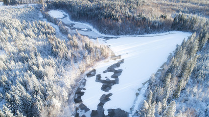 Winter season aerial view of frozen lake in the middle of forest.