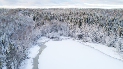 Obraz premium Winter season aerial view of frozen lake in the middle of forest.