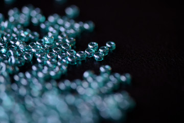 Scattered seed beads aquamarine color on a dark surface close up