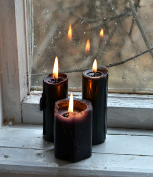 Burning black candles against the old window. Occult, esoteric, divination and wicca concept, mystic background