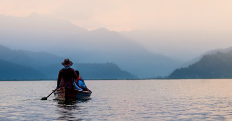 Tourists on old small boat sailing on the Phewa lake on the sunset, Nepal