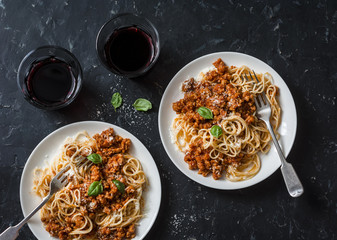 Chicken bolognese spaghetti and glasses of red wine on dark background, top view. Delicious lunch in a mediterranean style, top view. Flat lay