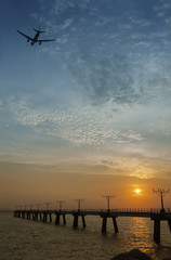 passenger plane fly up over take-off runway from airport at sunset