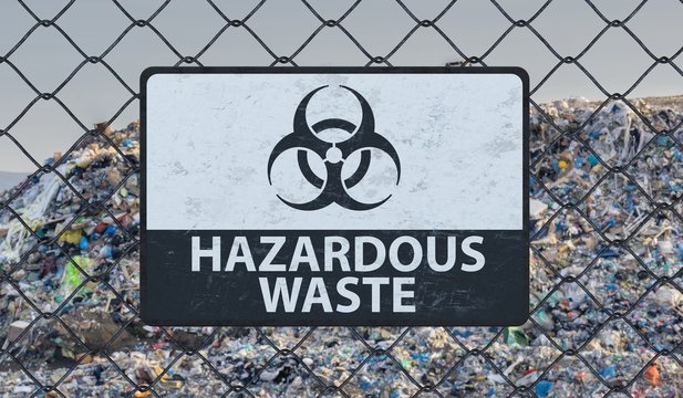 3D rendered illustration of hazardous waste sign on chain link fence. Landfill in background.
