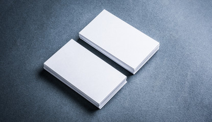 Two stacks of blank paper business cards on textured background.