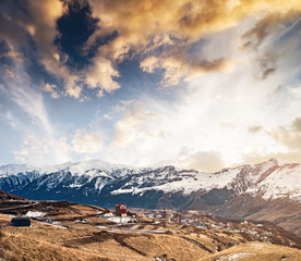 Beautiful mountains landscape in Georgia with road and houses in Gudauri at sunset