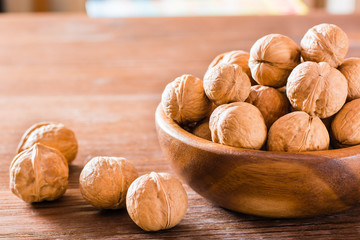 Walnuts in a plate and lie on a wooden table