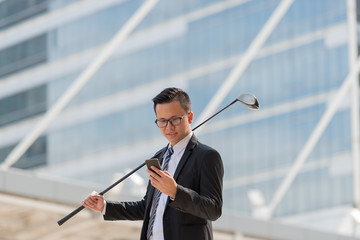Successful businessman in suit. hand holding golf equipment and smartphone standing the city. success concept in city background