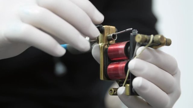 A tattoo artist is setting up his electric tattoo machine. Slow motion.