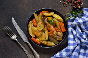 Homemade dinner. Chicken baked with potatoes, carrots with herbs on a dark background.