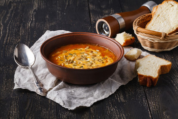 Vegaterian hot pumpkin soup serving in bowl on rustic table