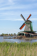 Naklejka premium One grey mill with orange wings near the water in Zaanse Schans (Netherlands)