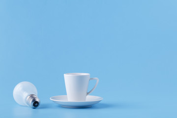 Energy for long day, coffee cup on blue with light bulb