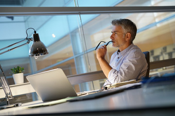 Businessman in office being thoughtful in front of laptop - Powered by Adobe