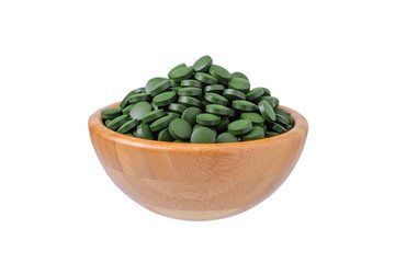 organic spirulina and chlorella pills in a wooden bowl isolated on white
