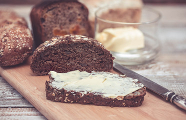 Rye bread with seeds of hemp and a kino. Healthy bread. Baguette and table knife and butter. Wooden background Clouse-up