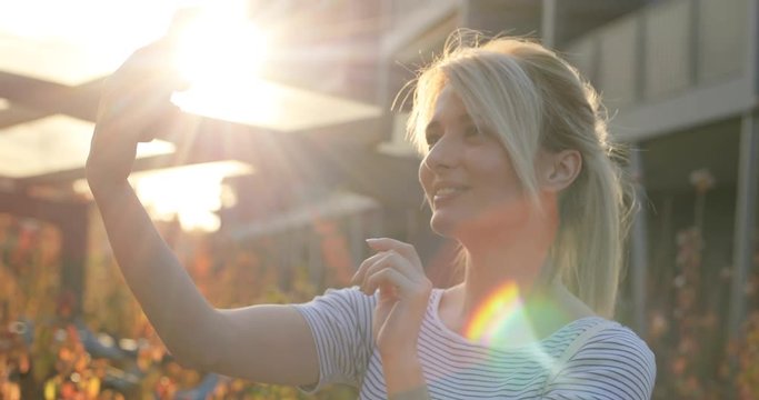 Summer Girl make a self portrait with smart phone. Close-up portrait of blond woman making faces and smiling for felfies
