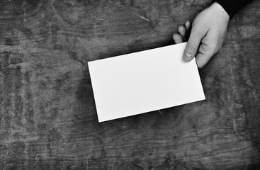 monochrome photo male hands holding a white blank sheet of paper