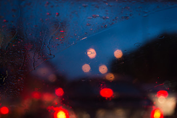Fototapeta na wymiar Abstract rain drops background with colorful traffic lights at night blur bokeh.