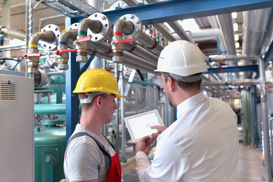 Teamwork in einer Industrieanlage - Arbeiter und Geschäftsmann vor Ort beim planen // 