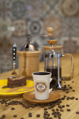 Fototapeta na wymiar A cup of coffee and a piece of cake placed on a table with a coffee maker in the background