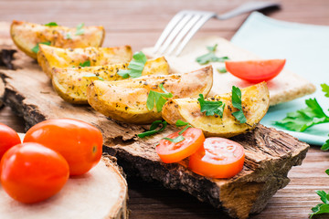 Slices of baked potatoes with spices and herbs on the bark of a tree