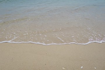 The waves beat at the beach with shell fragments. Nature background concept.