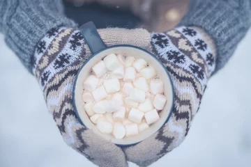Photo sur Plexiglas Chocolat mains de la jeune fille tenant une tasse avec du chocolat chaud sur fond de neige